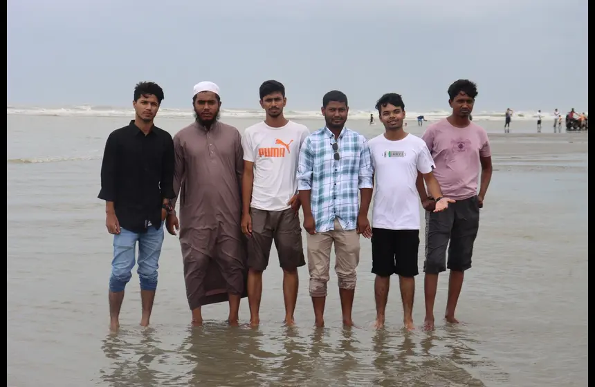 Team members posing together for a group photo at Cox's Bazar beach during company retreat
